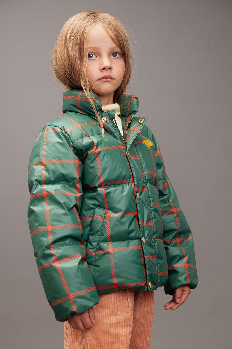 Child wearing a green plaid jacket on a gray background - Little-ish