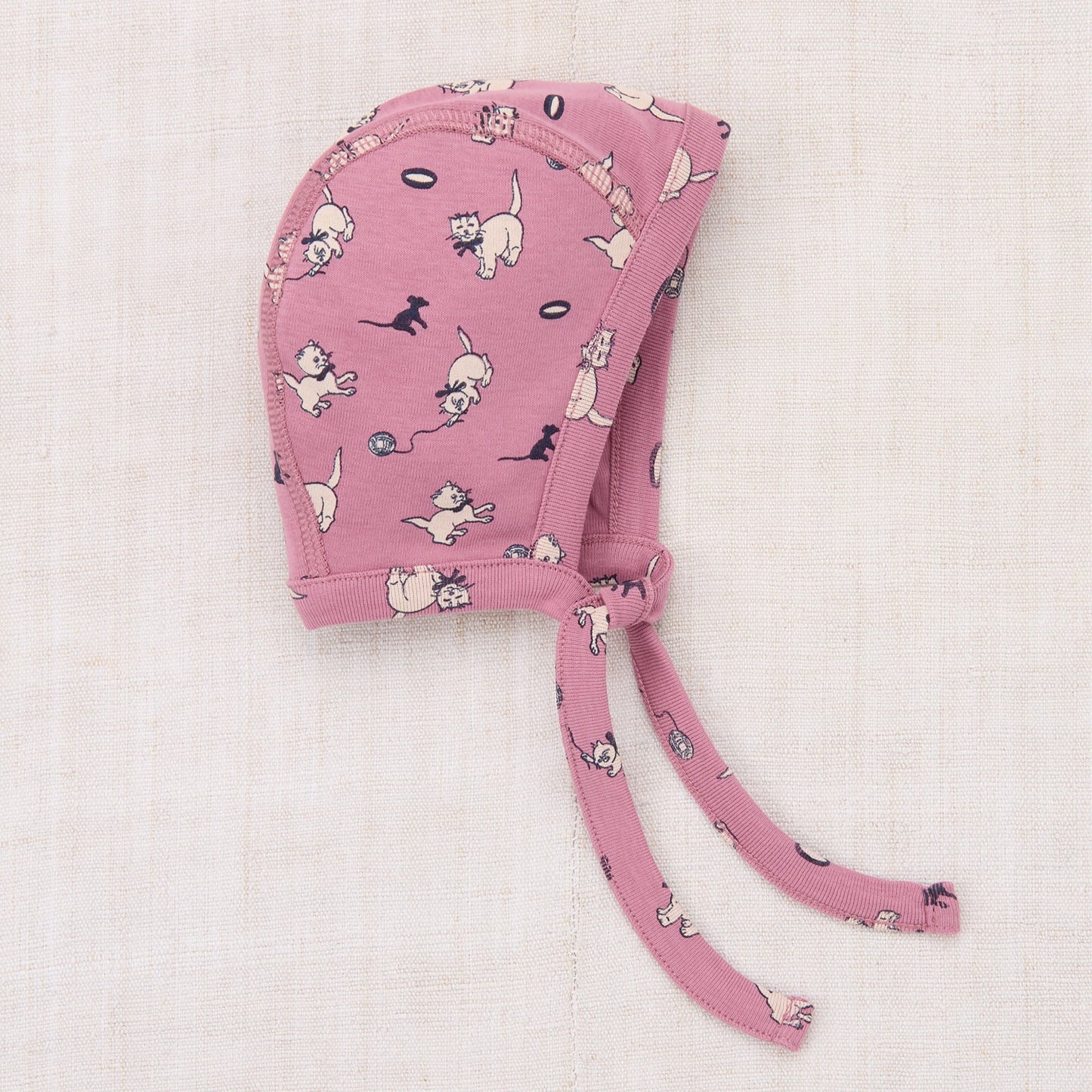 Pink baby bonnet with dog pattern on a light pink background