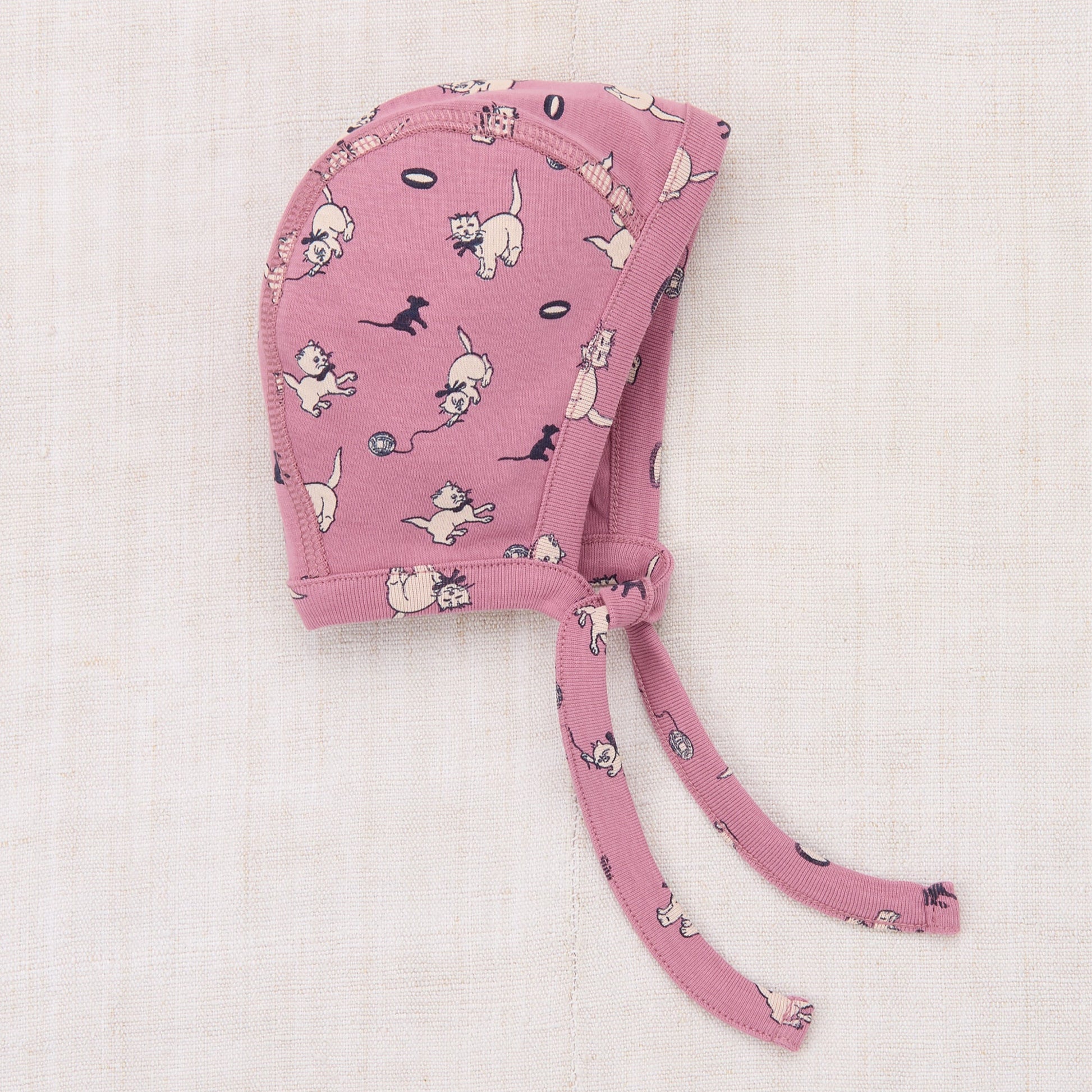 Pink baby bonnet with dog pattern on a light pink background