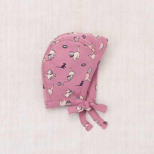 Pink baby bonnet with dog pattern on a light pink background