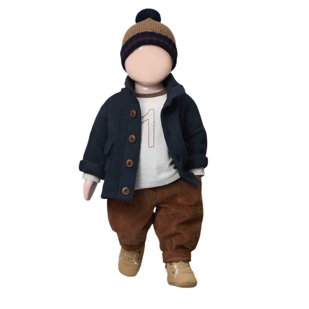 Toy figure of a child wearing a navy coat, brown pants, and a knit hat on a white background - Little-ish