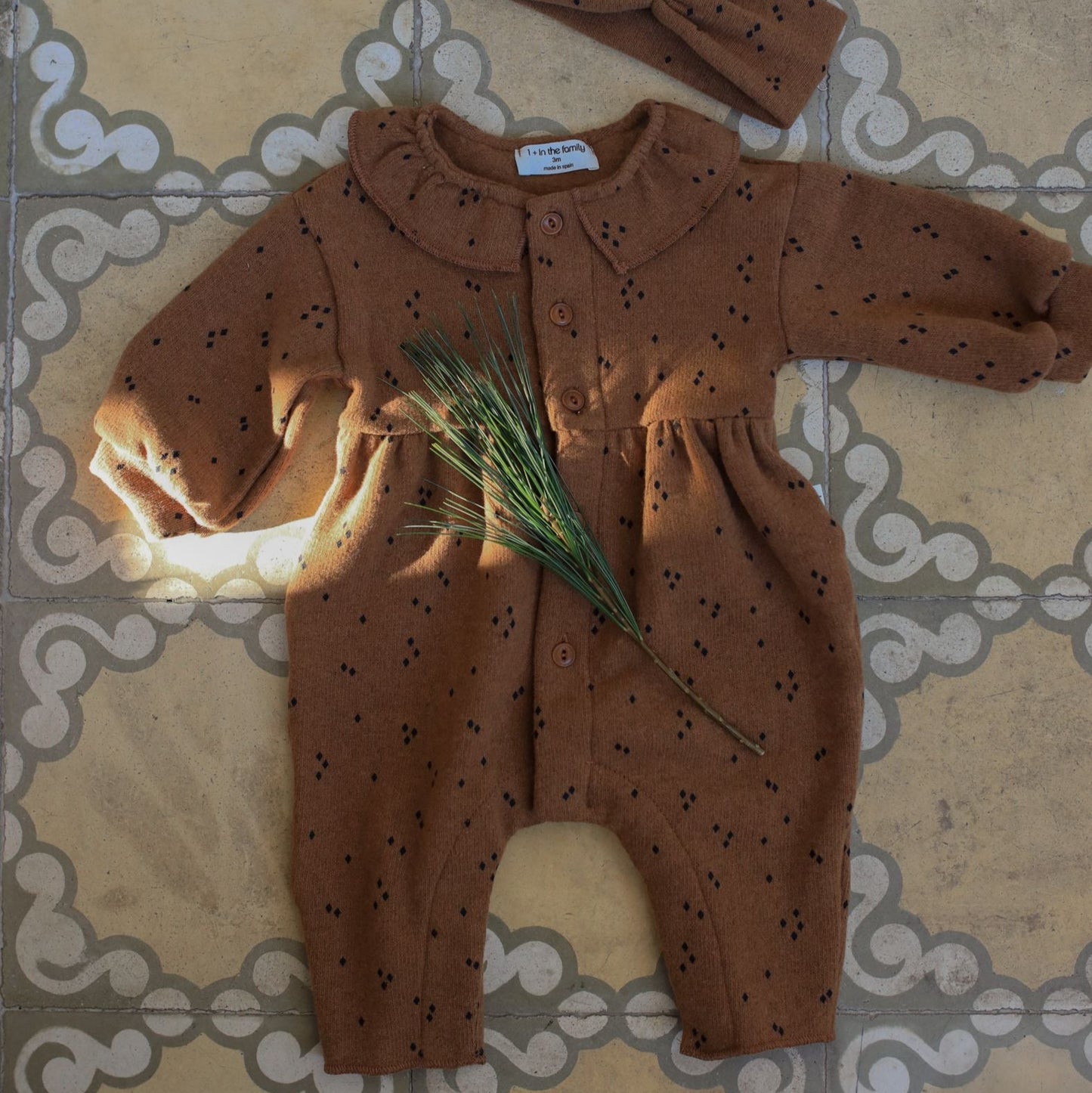 Brown baby outfit with matching hat on a tiled floor