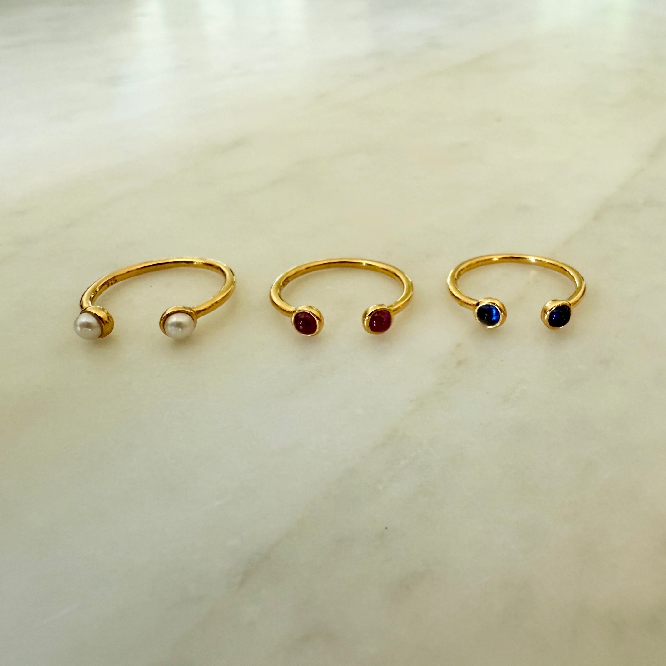 Three gold nose rings with gemstones on a light background - Little-ish