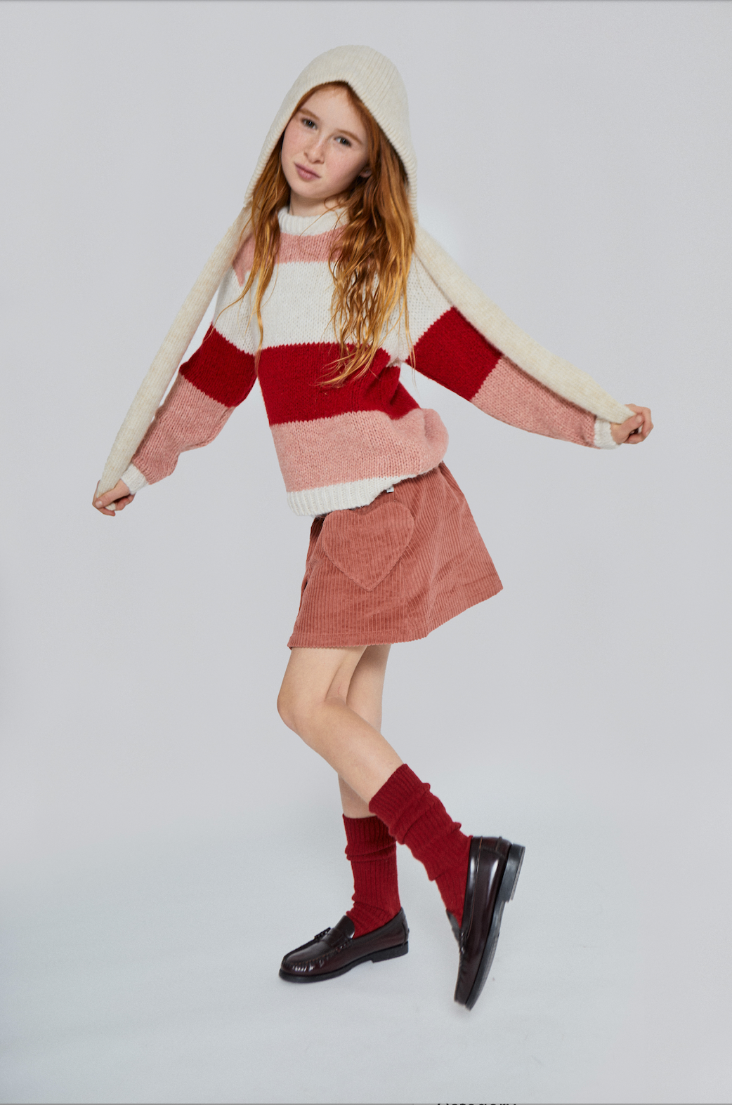 Person wearing a striped sweater, skirt, and knee-high socks on a white background - Little-ish