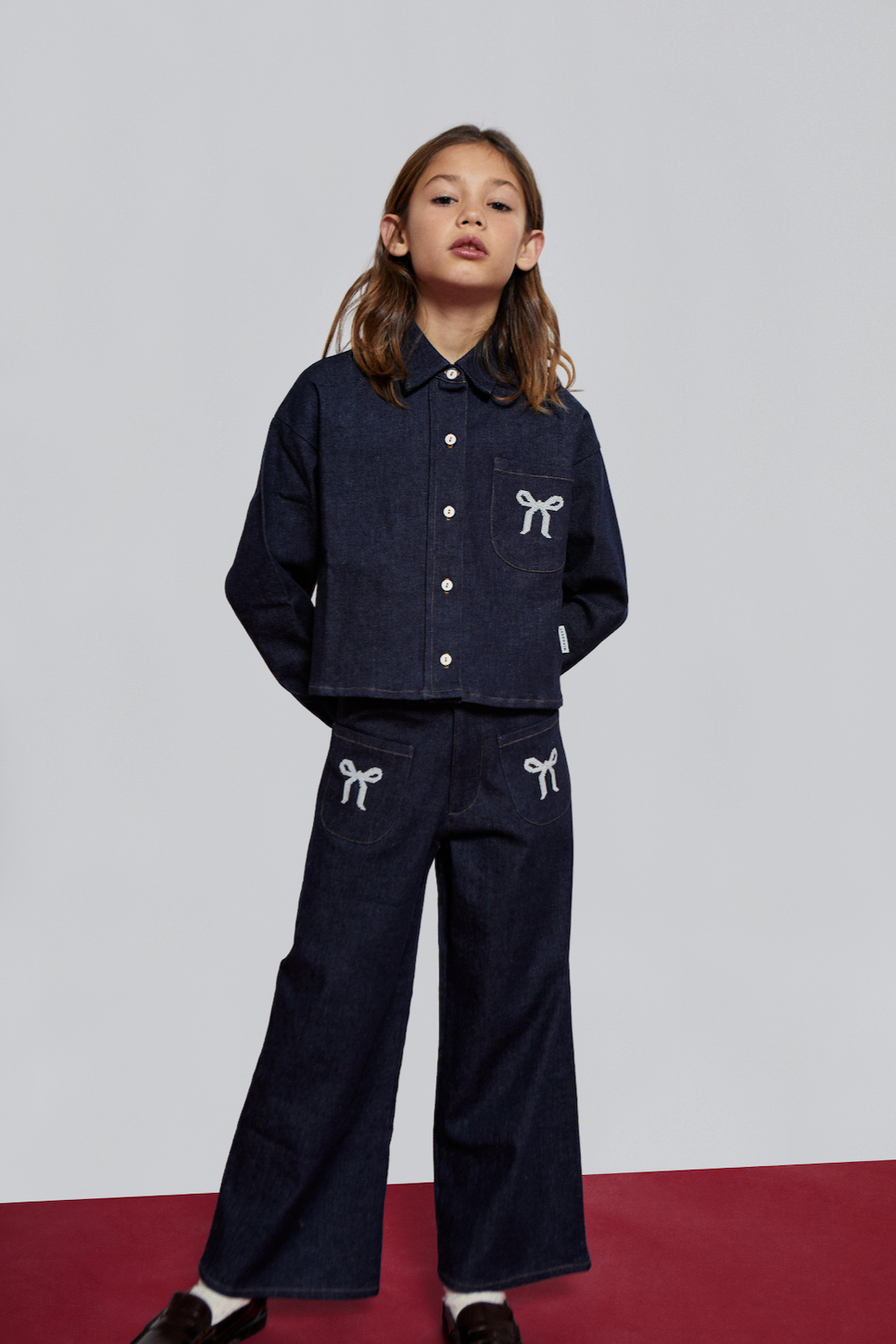 Child wearing a navy blue outfit with white accents on a plain background - Little-ish