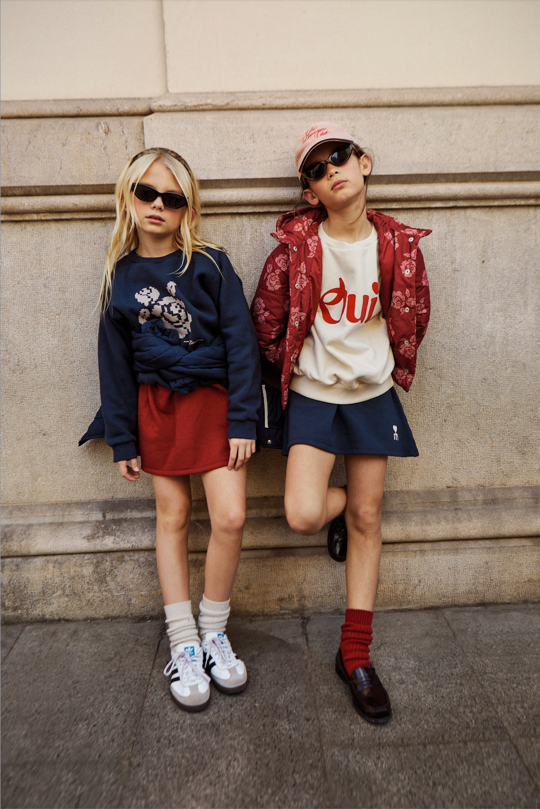 Two children posing against a stone wall, wearing stylish outfits. - Little-ish