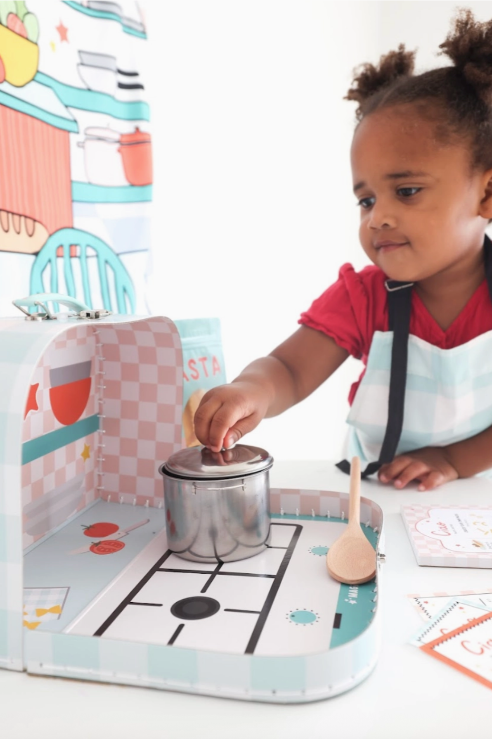 Child playing with a toy kitchen set on a white surface