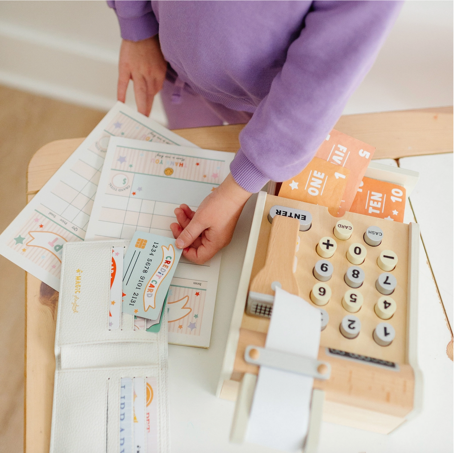 Child playing with a wooden toy cash register and card reader.