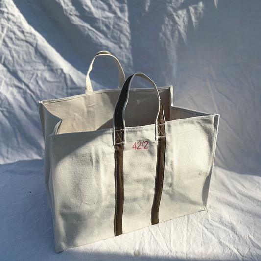 Large beige tote bag with brown handles on a textured white background