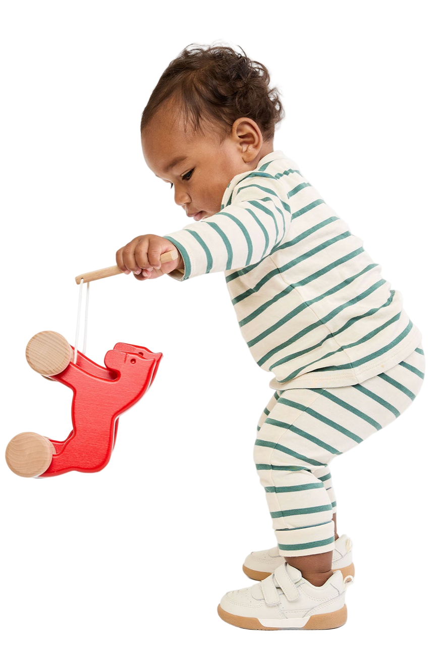Child playing with a red toy on a white background - Little-ish