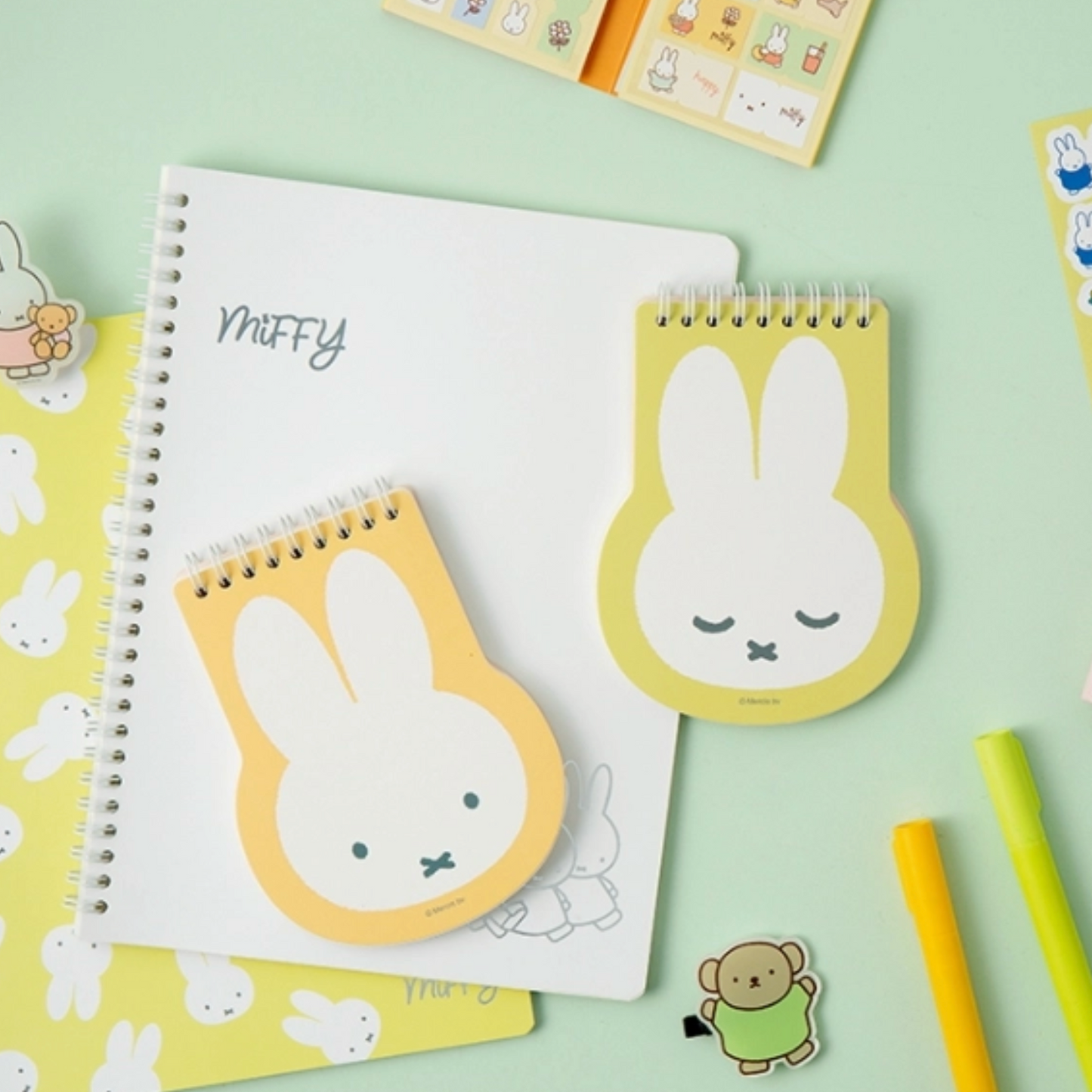 Notebooks and stationery items with cartoon character design on a light green background