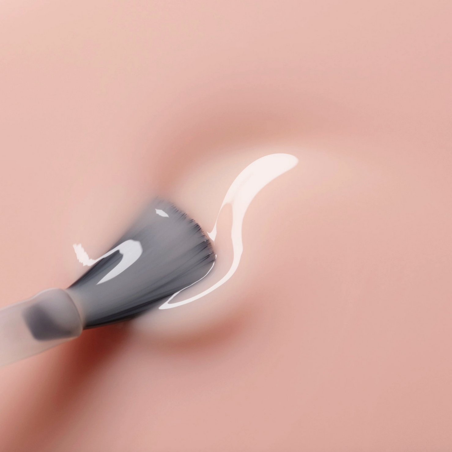 Close-up of a makeup brush applying cream to skin with a blurred background - Little-ish