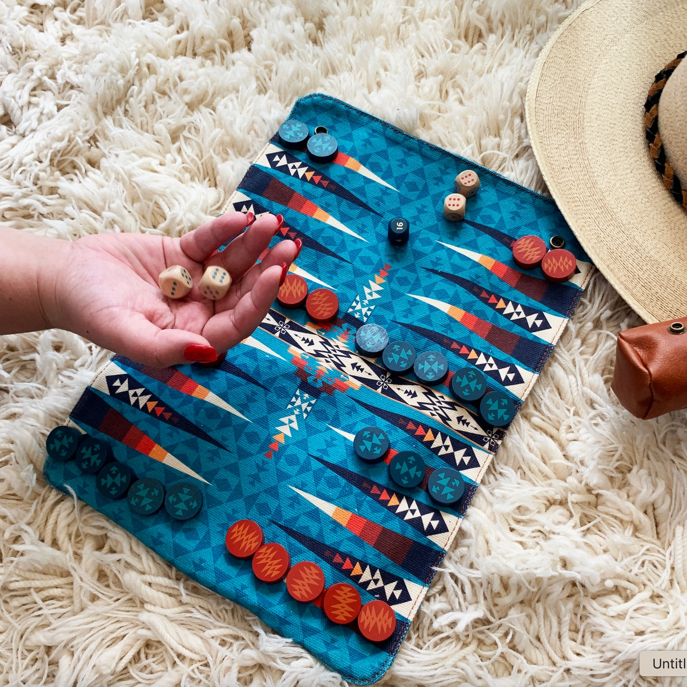 Backgammon set with dice on a patterned board on a fluffy white surface.