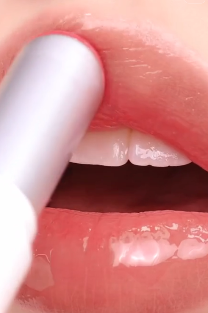 Close-up of a person applying lip balm to their lips.