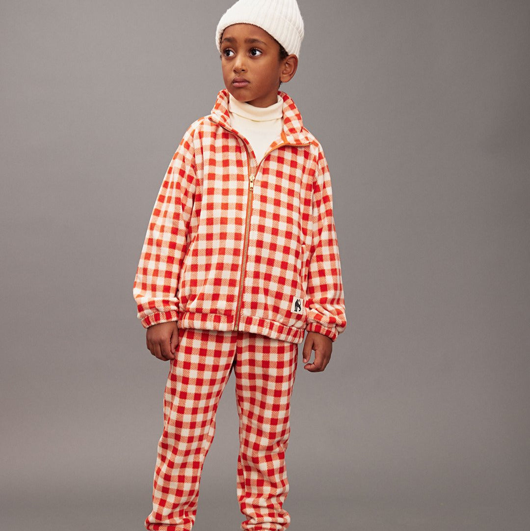 Child wearing a red and white checkered outfit on a gray background
