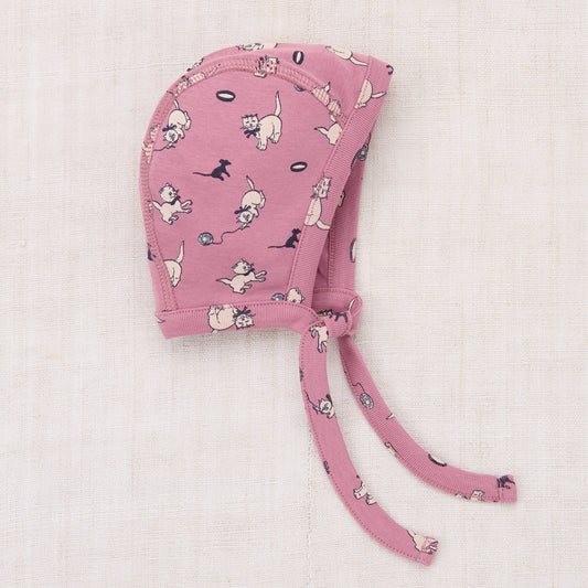 Pink baby bonnet with dog pattern on a light pink background