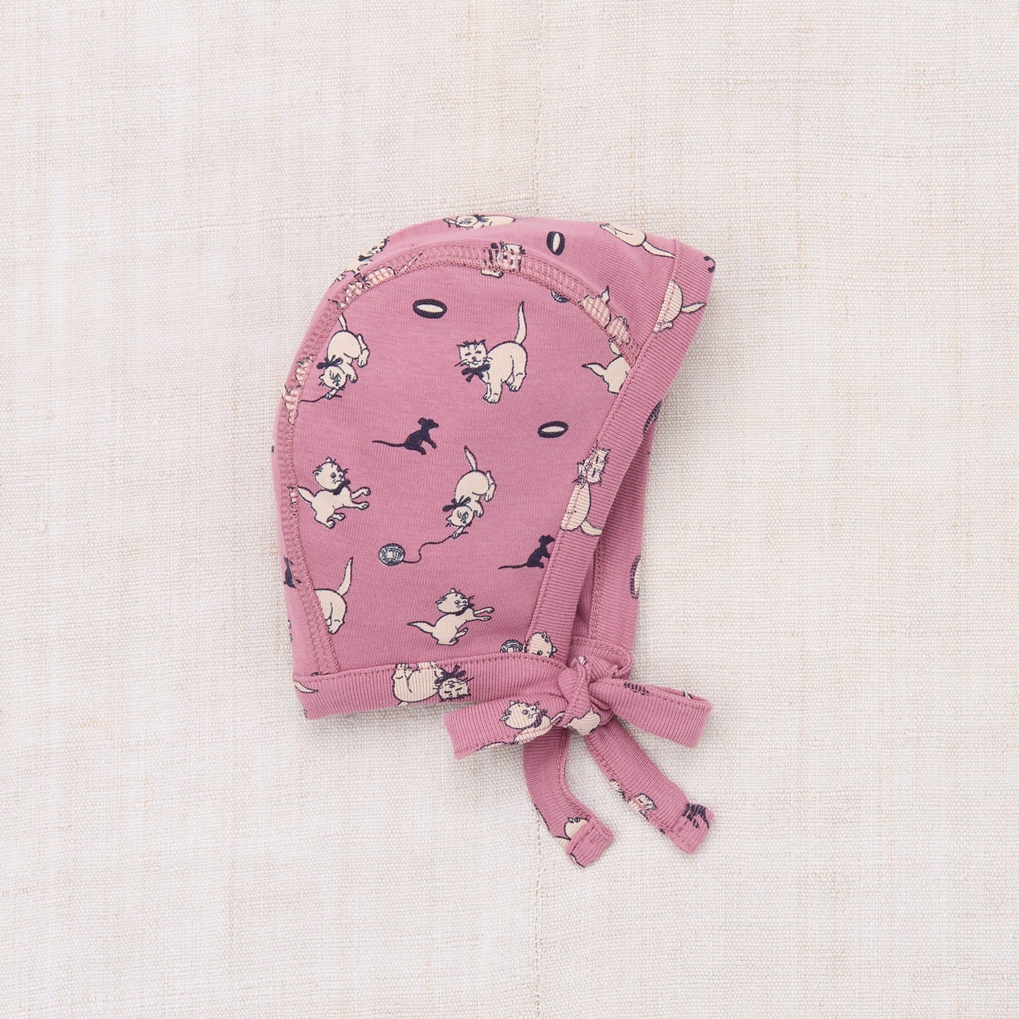 Pink baby bonnet with dog pattern on a light pink background