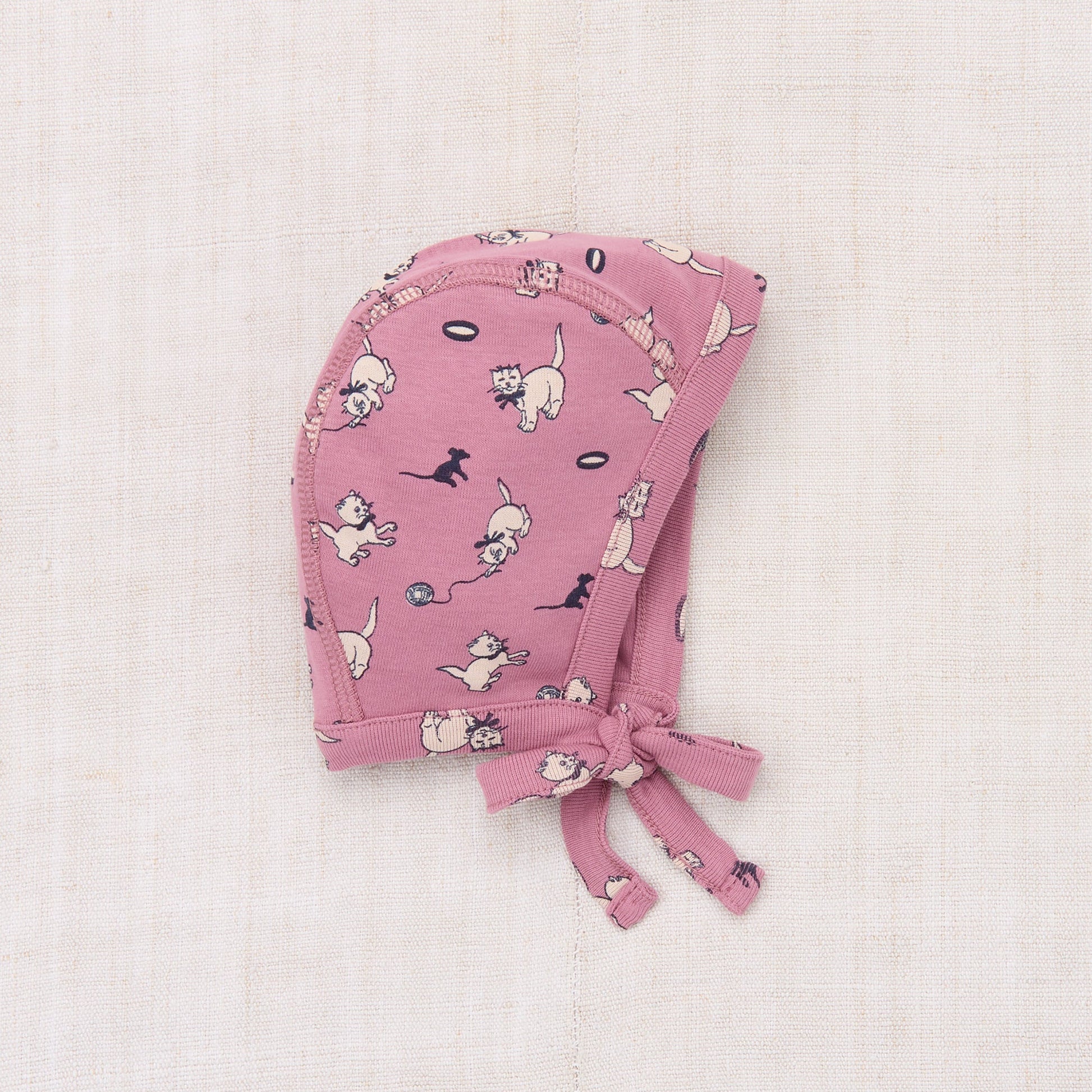 Pink baby bonnet with dog pattern on a light pink background