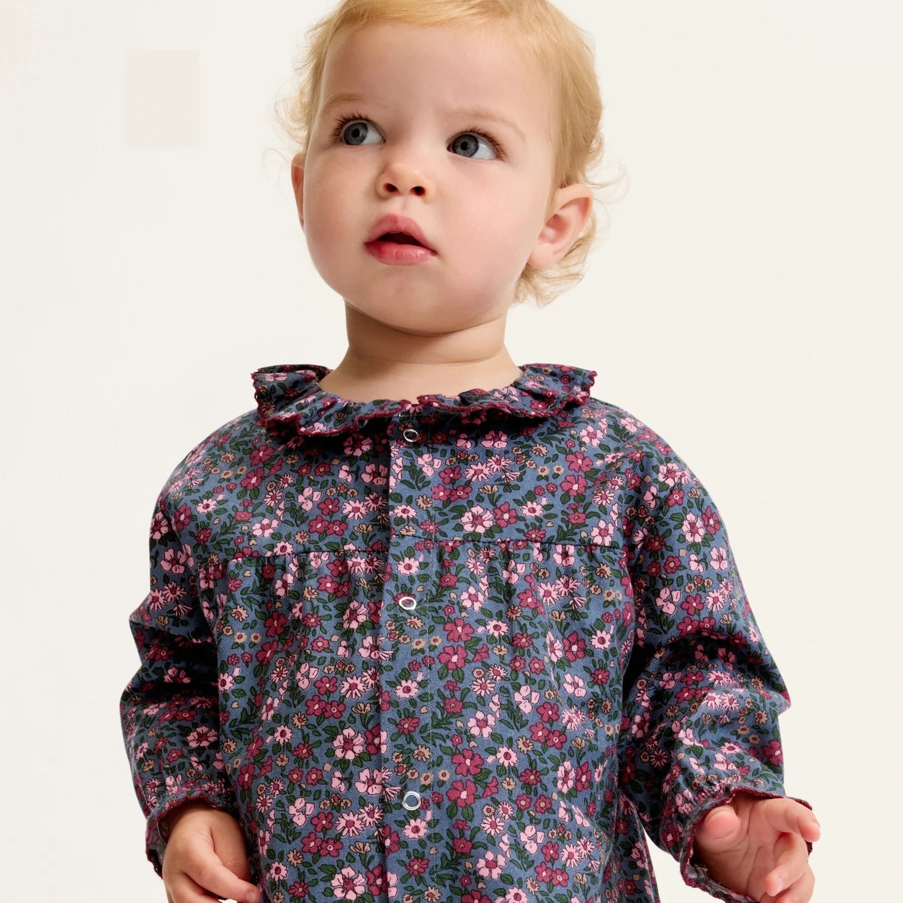 Child wearing a floral dress on a plain background