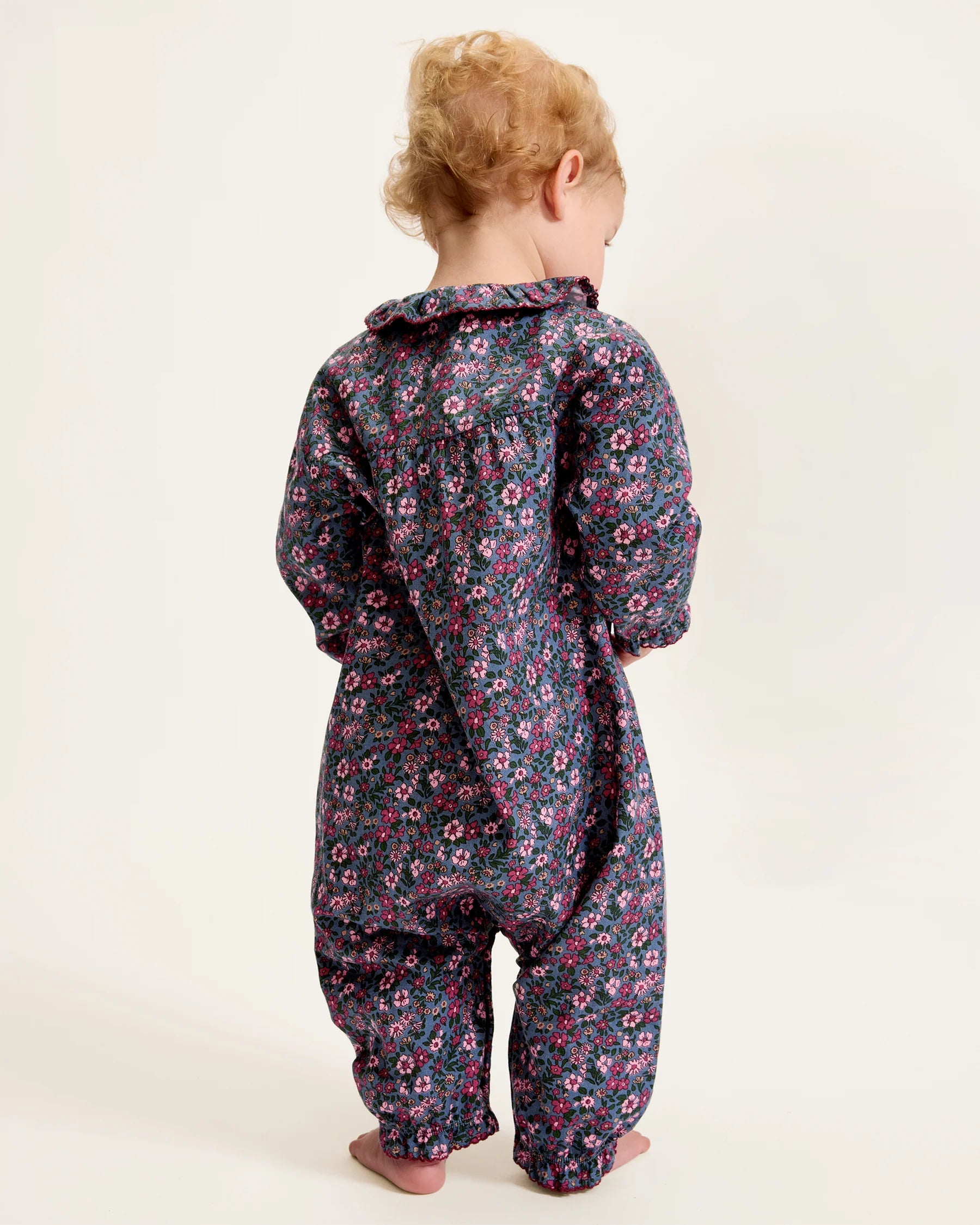 Child wearing a floral onesie on a white background