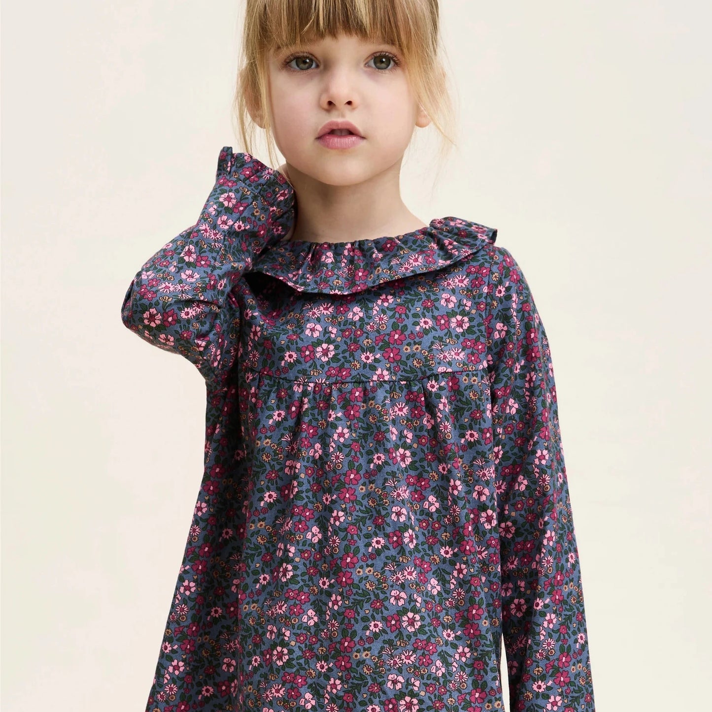Young girl wearing a floral dress on a plain background