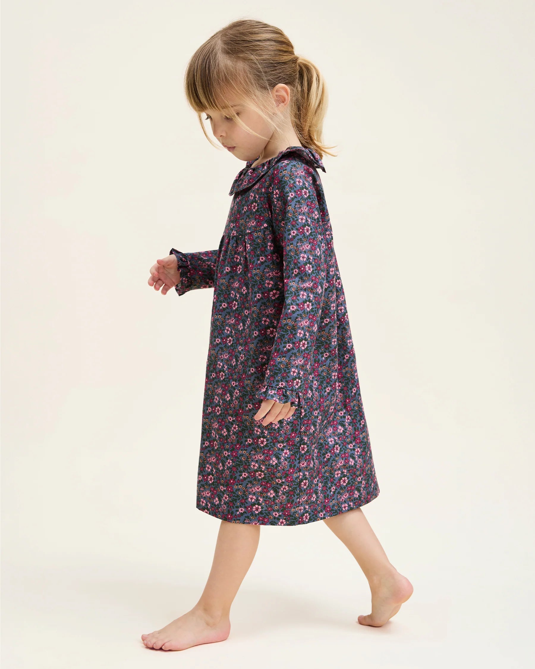 Young girl wearing a floral dress on a plain background
