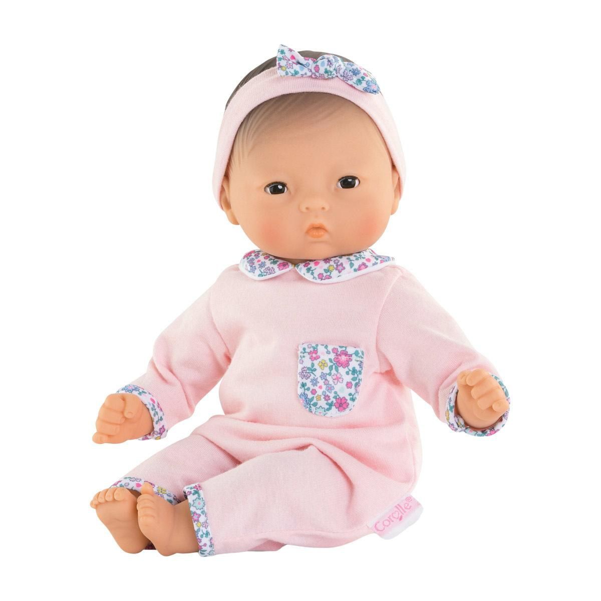 Baby doll in pink outfit with floral details on a white background