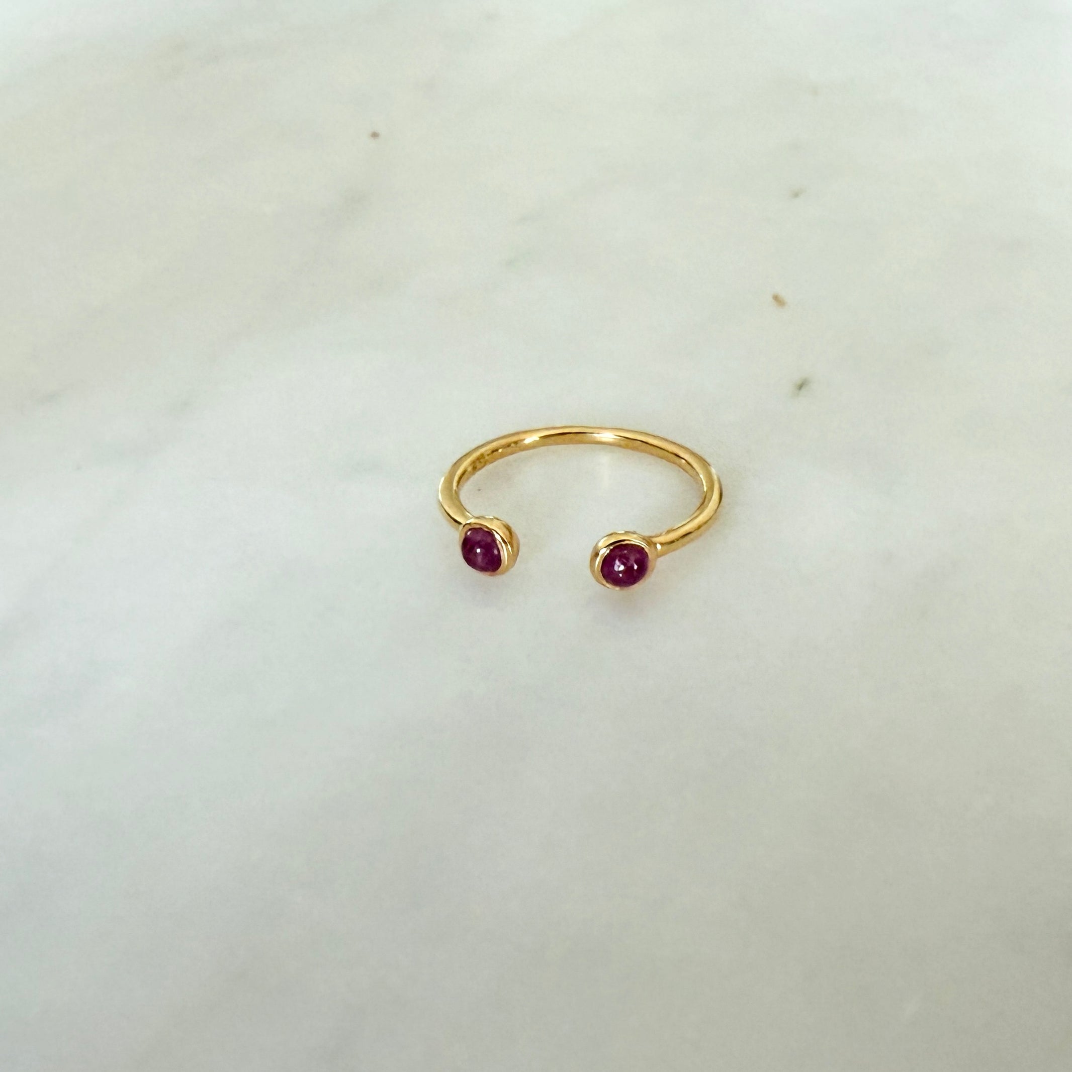 Gold ring with two red gemstones on a light gray background - Little-ish