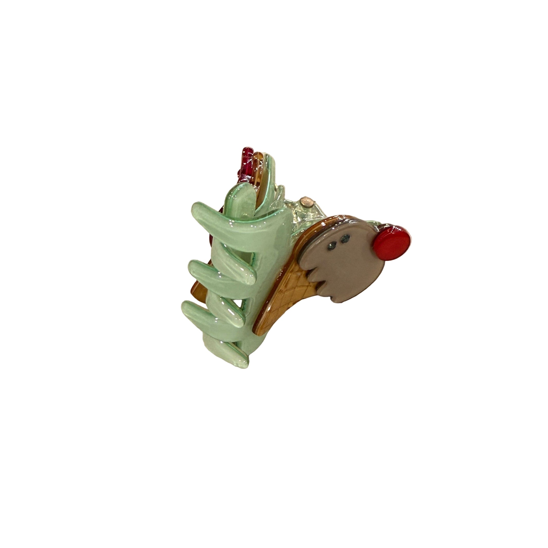 Decorative hair clip with a green base, red accents, and a small animal figure on a beige surface. - Little-ish