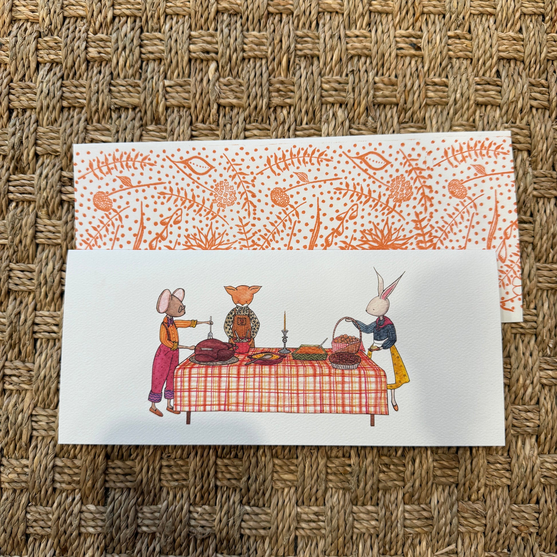Two greeting cards with festive designs on a woven surface