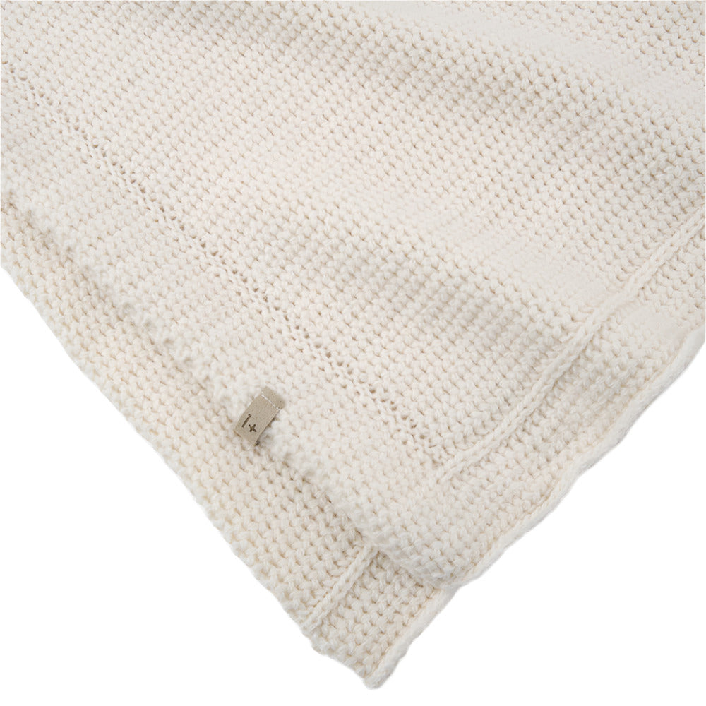 Close-up of a textured ecru wool knit blanket with a corner folded over on a white background - Little-ish