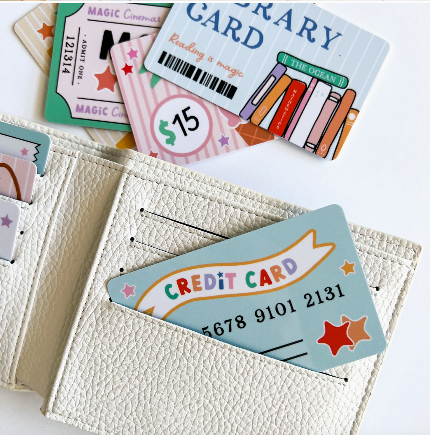Collection of various cards including a library card and a credit card, with a white wallet holding a credit card. - Little-ish