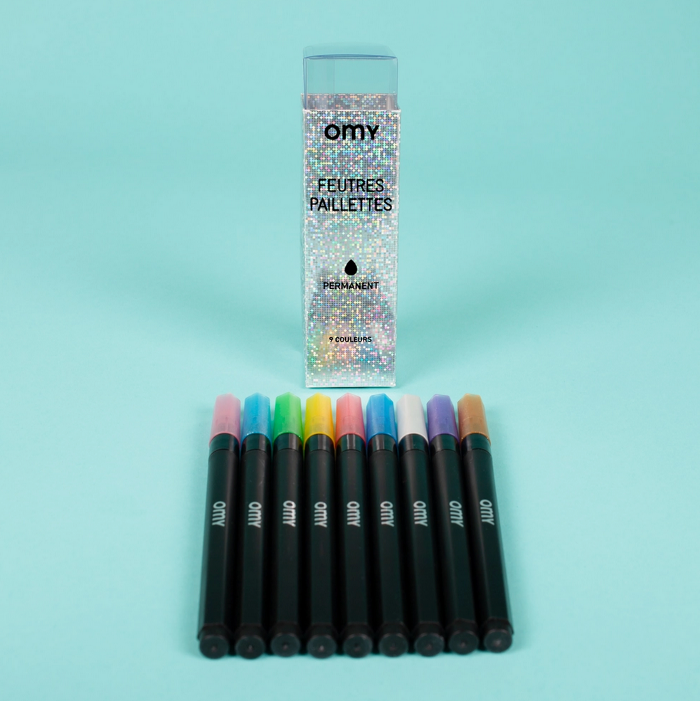 Set of colorful markers with a packaging box on a light blue background - Little-ish