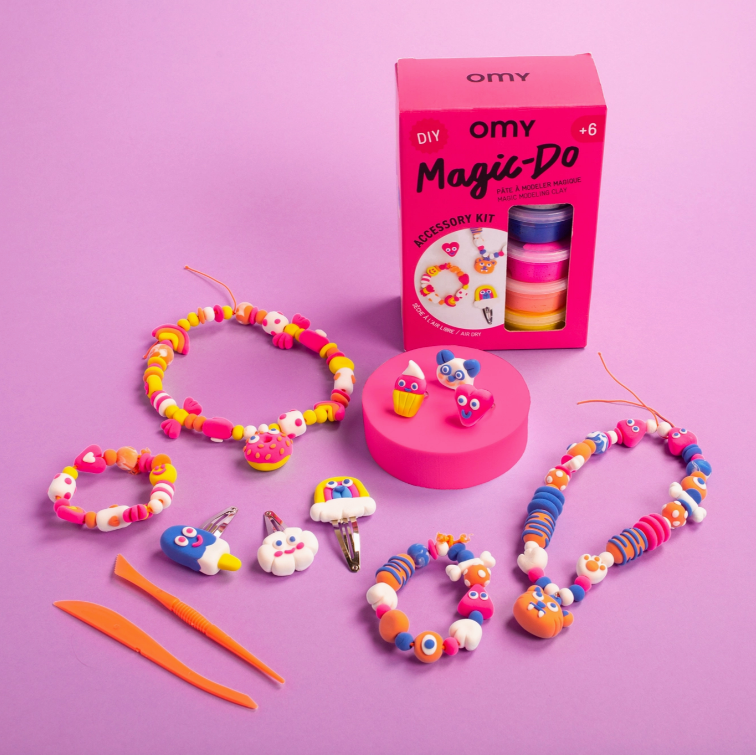 Colorful beaded bracelets and accessories with OMY packaging on a pink background - Little-ish