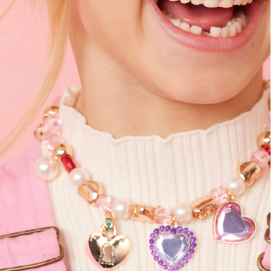 Child wearing a colorful bracelet with heart-shaped charms on a pink background