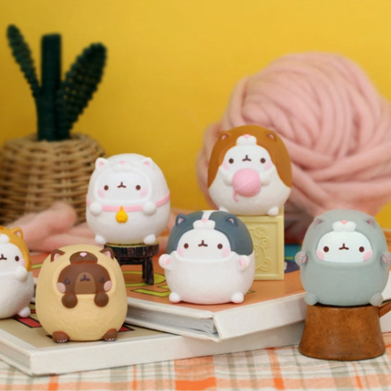 Set of cute animal-themed figurines on a table with a yellow wall and plant in the background. - Little-ish