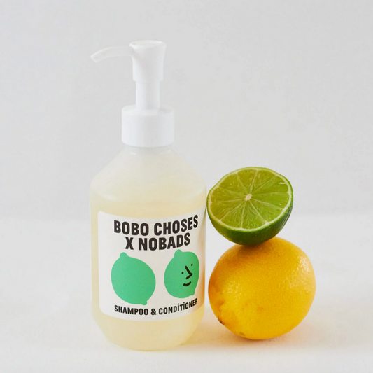 Bottle of Bobo Choses x Nobads shampoo and conditioner with a lemon and lime on a white background
