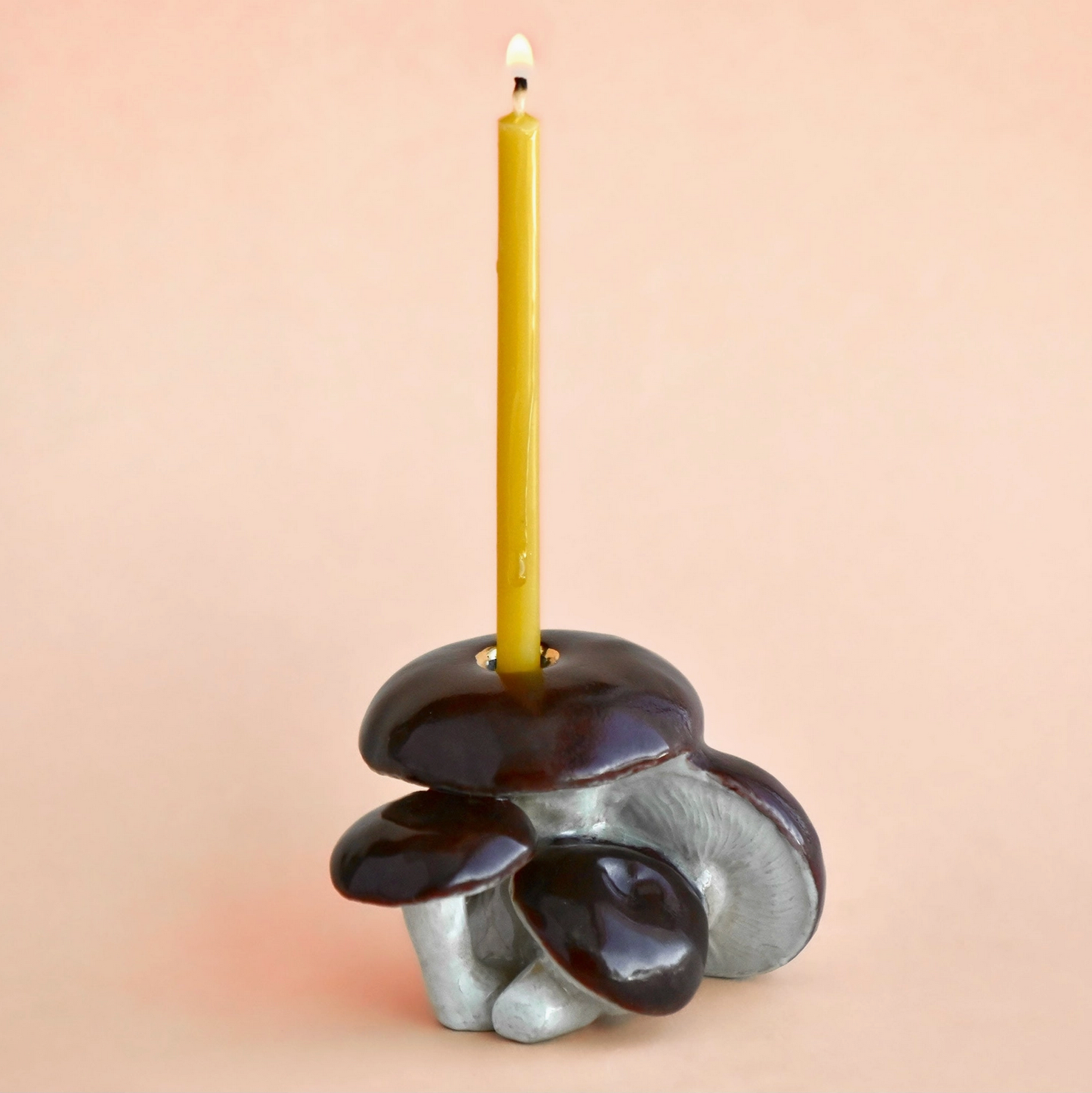 Ceramic candle holder with a yellow candle on a beige background