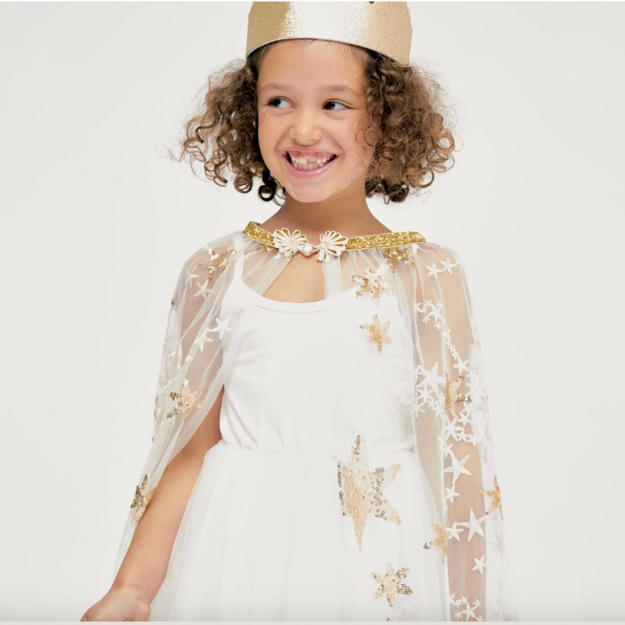 Child wearing a white dress with gold star designs and a matching headband on a white background - Little-ish