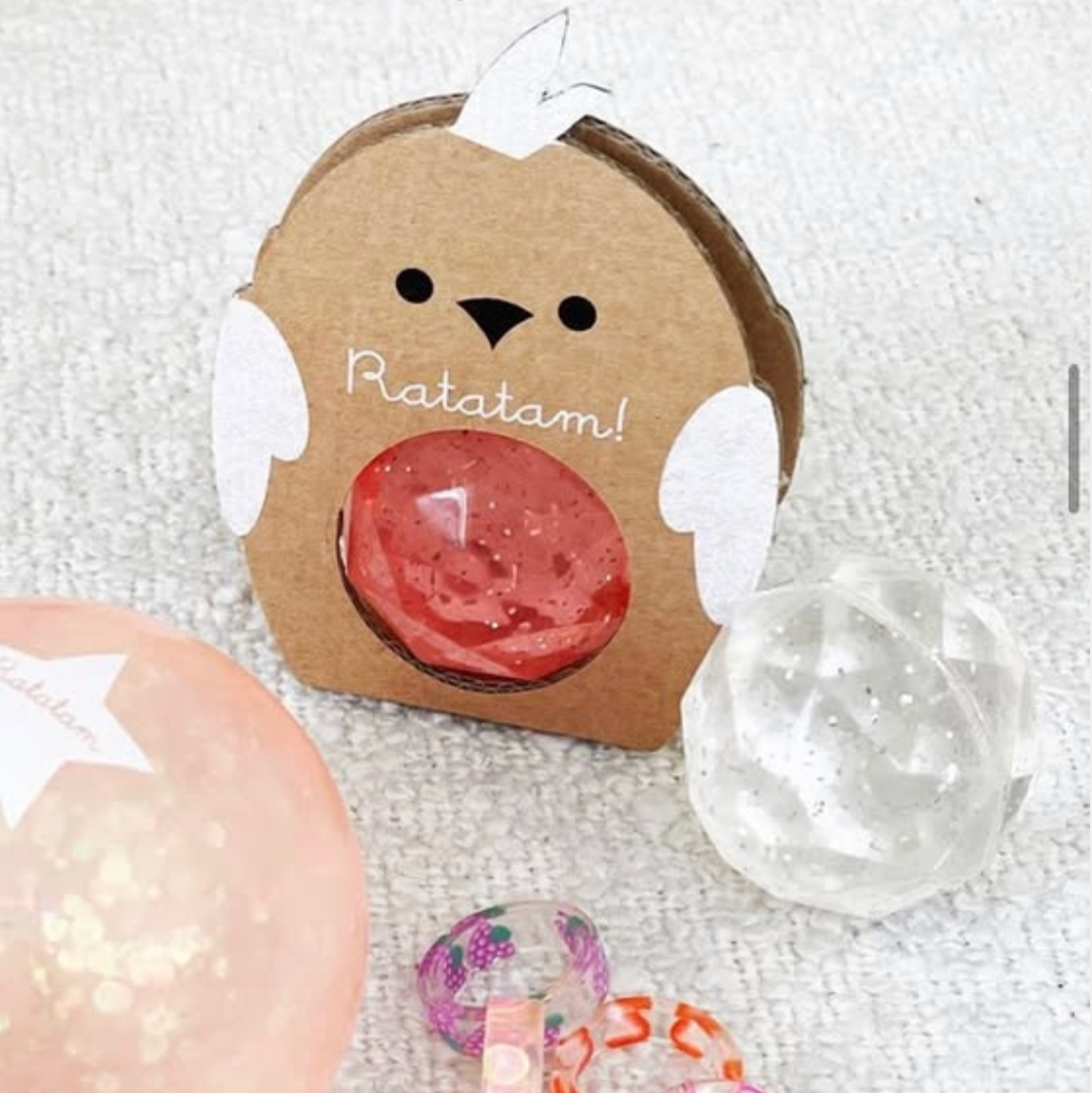 Cardboard container with a cartoon rat design and small items on a textured surface