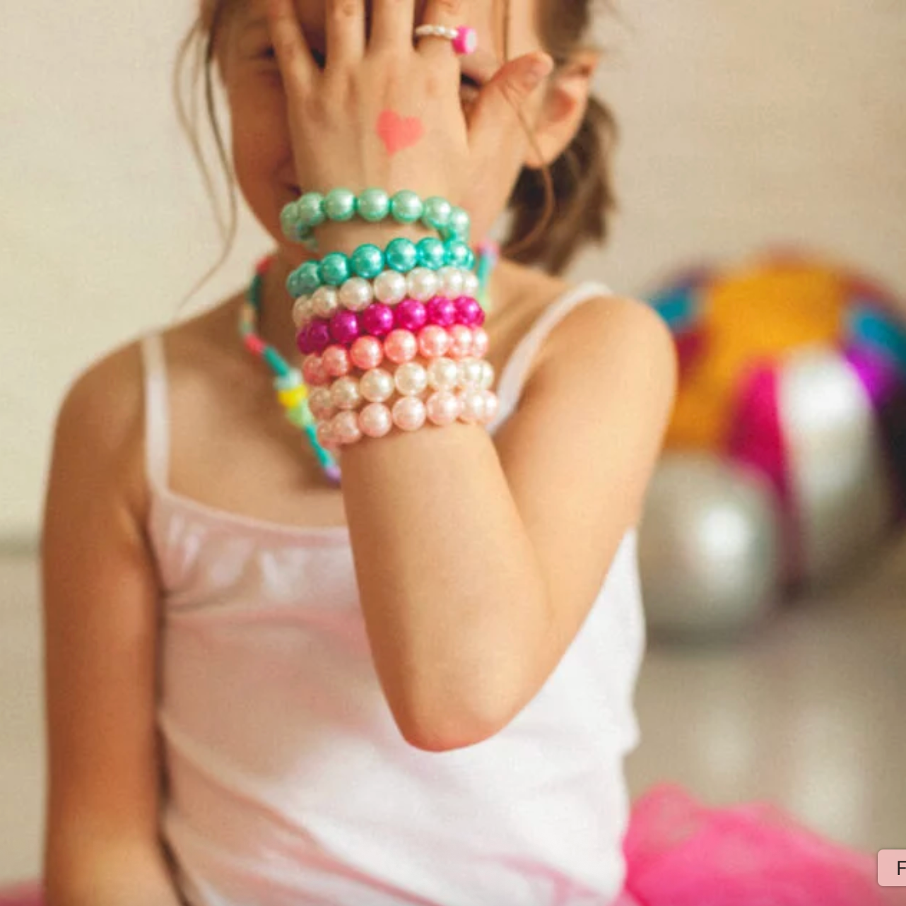 Child wearing colorful beaded bracelets with a blurred background - Little-ish