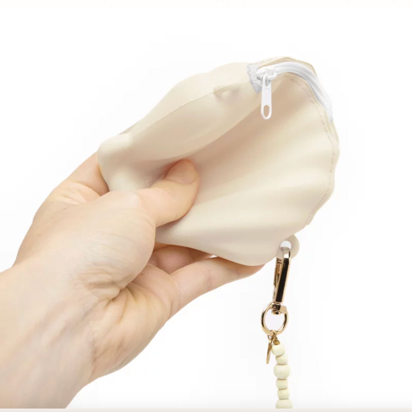 Hand holding a beige silicone key case with a keychain on a white background