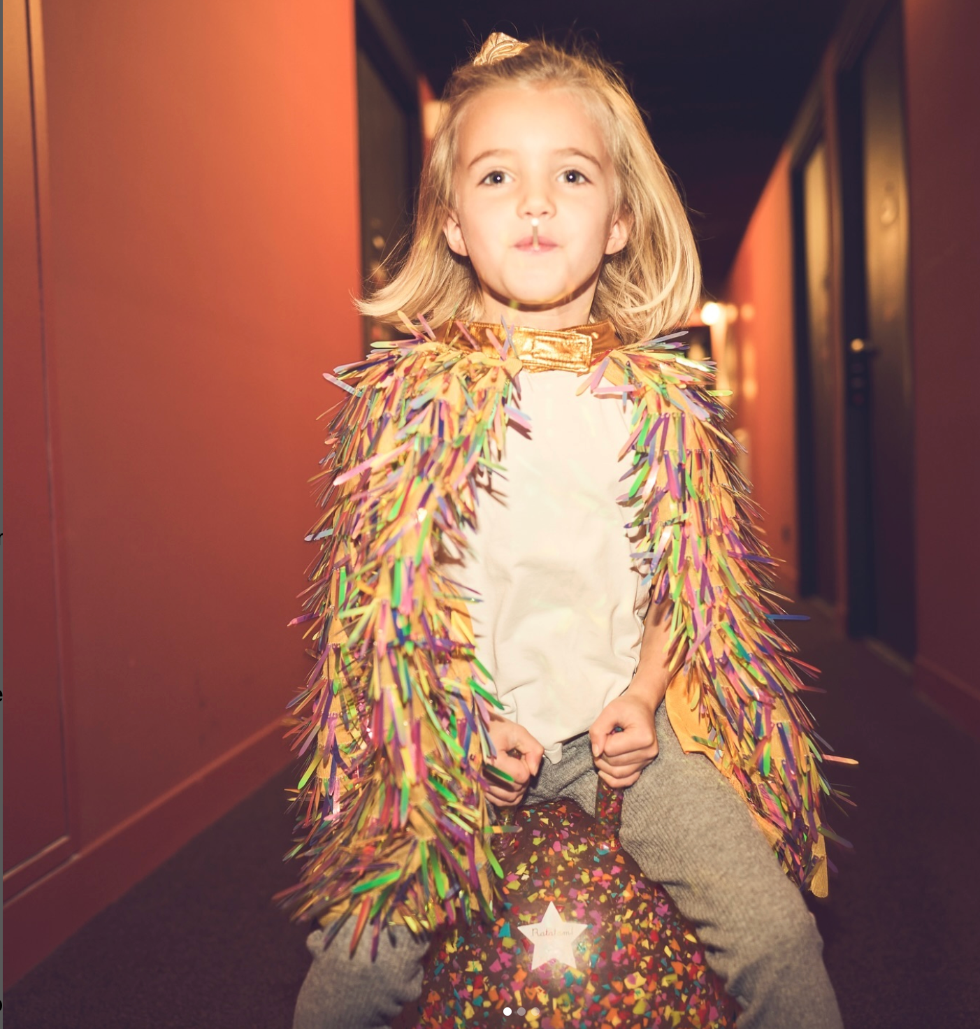 Child wearing a colorful costume with a star design in a hallway.