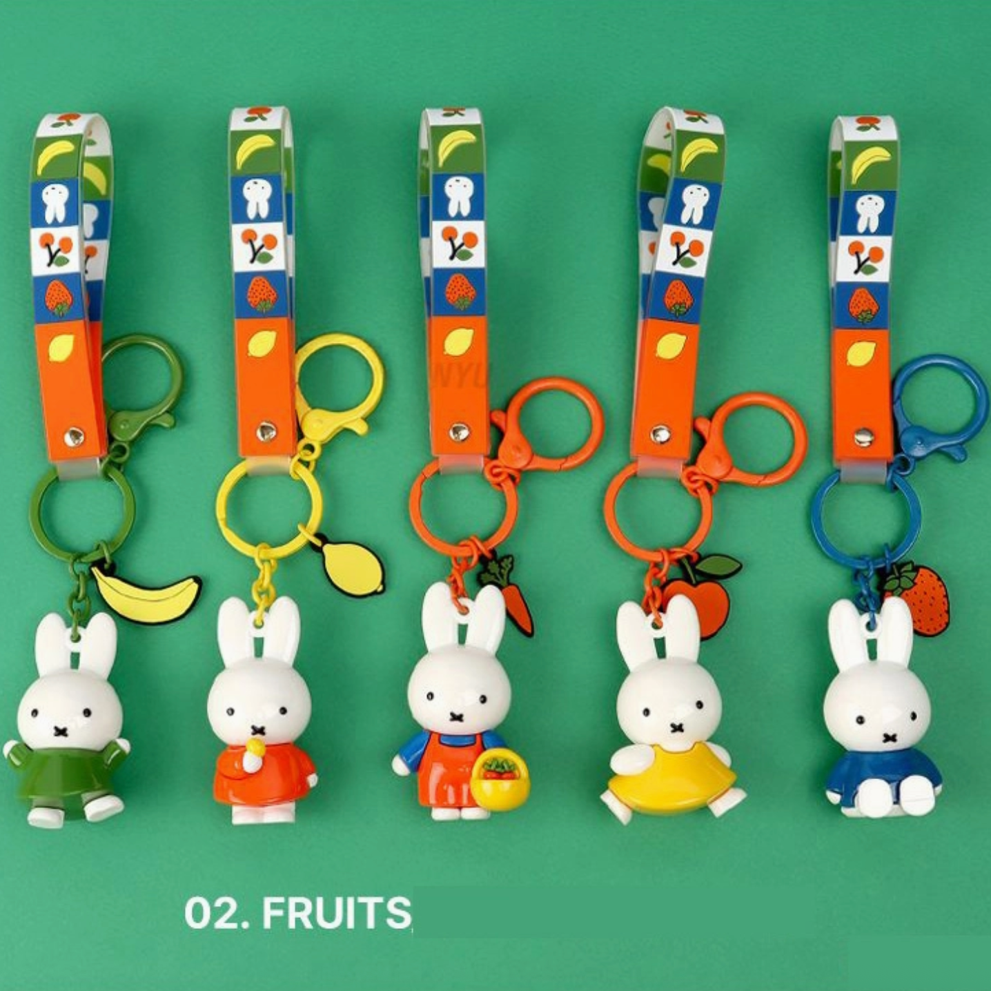 Set of keychains with cartoon characters and fruit-themed designs on a green background - Little-ish