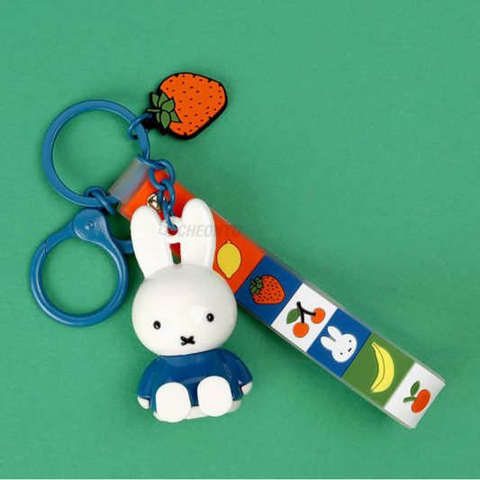 Keychain with cartoon rabbit character and colorful strap on a green background