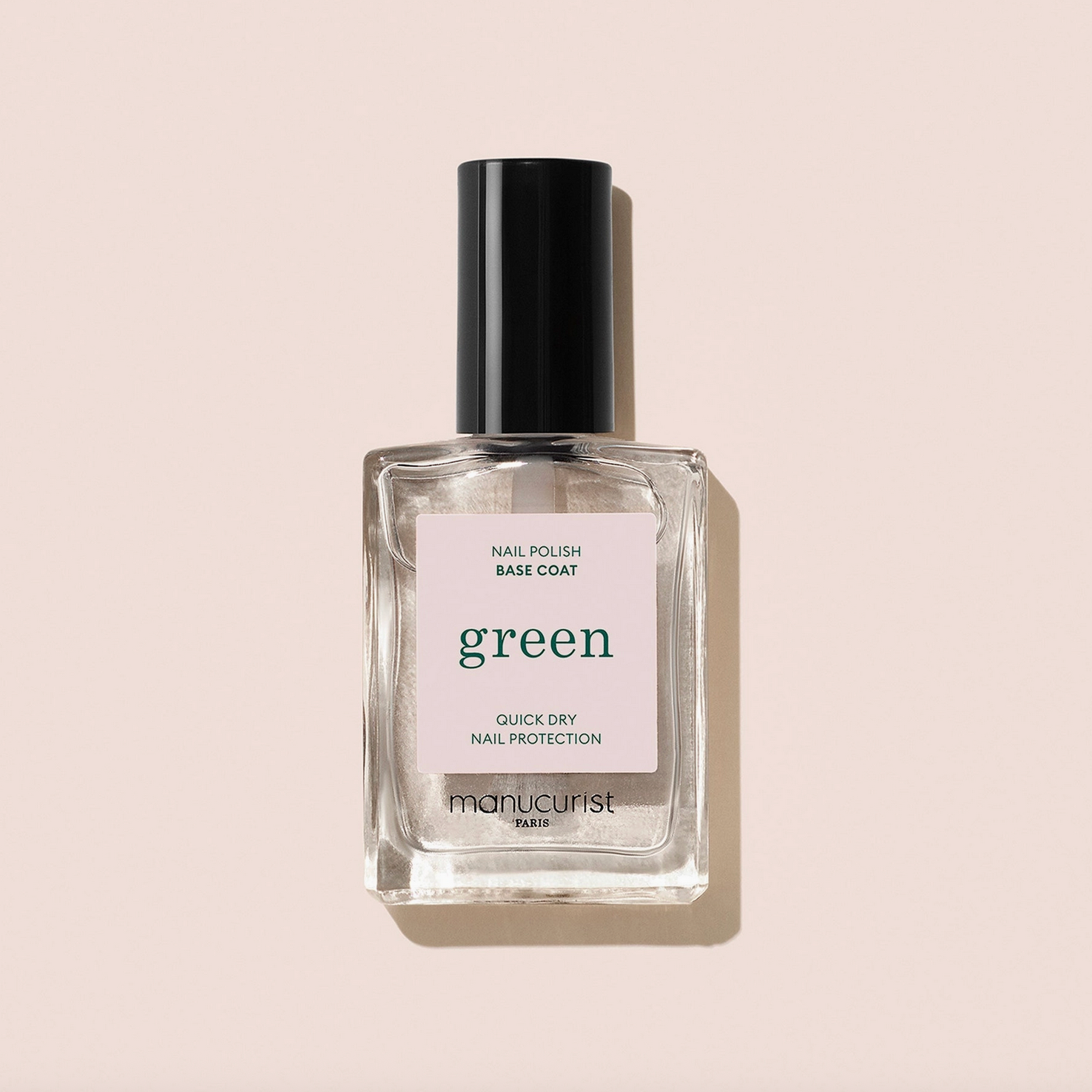 Bottle of nail polish base coat labeled 'green' on a beige background - Little-ish