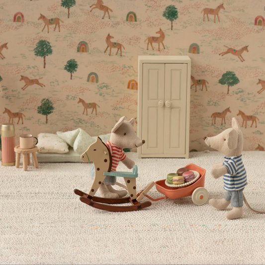 Children's room with toys, a lamp, and a cabinet against a wallpapered wall with animal patterns.