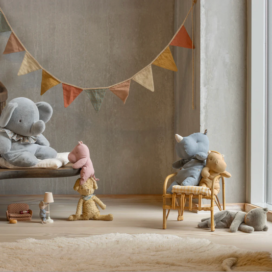Children's room with plush toys on chairs and a colorful banner on the wall.
