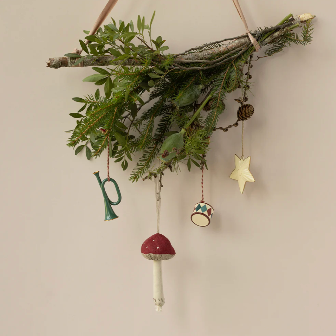 Decorative mistletoe with hanging ornaments on a beige wall - Little-ish