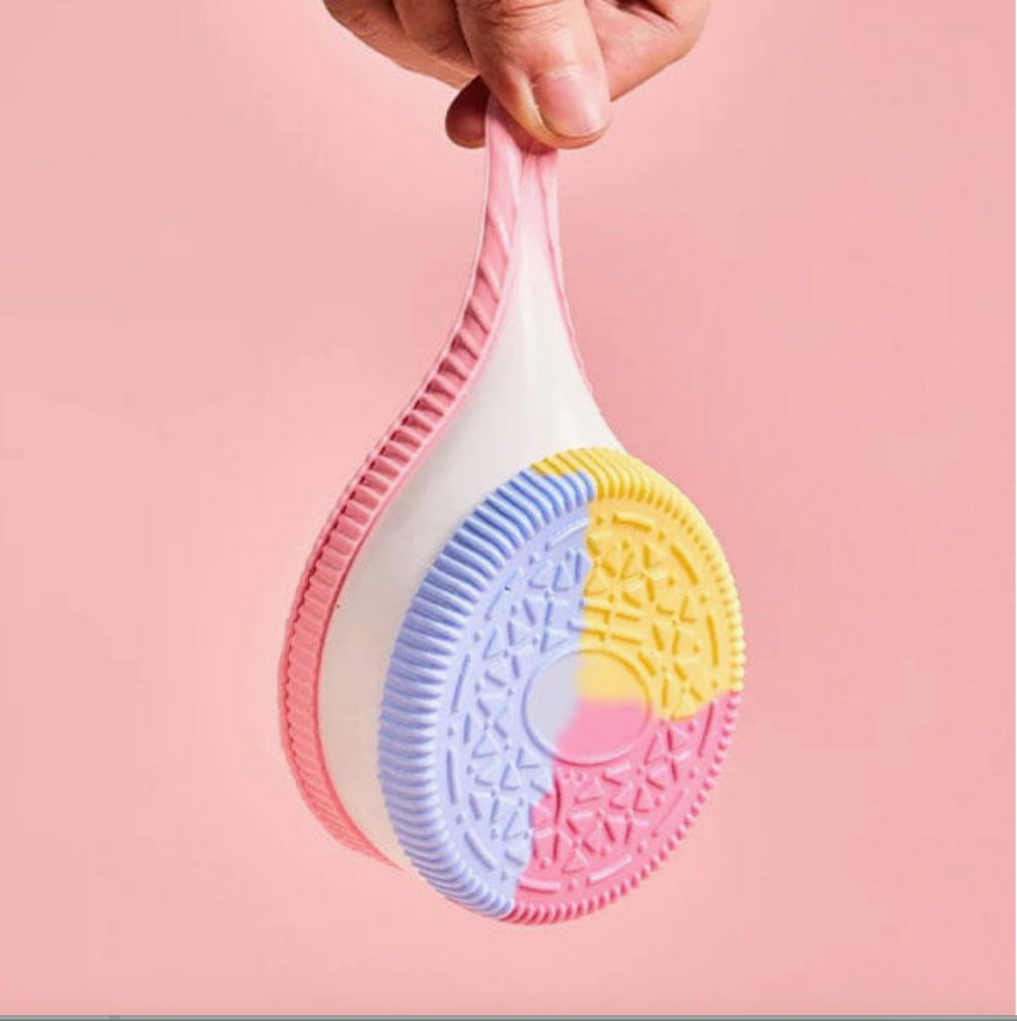 Colorful scrubber held by a hand against a pink background